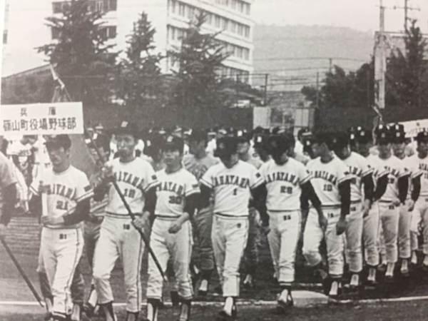 篠山長役場野球部のプラカードと優勝旗をもって行進している白黒写真