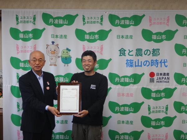 市長と大阪さんが満面な笑みで賞状を持ち、記念写真