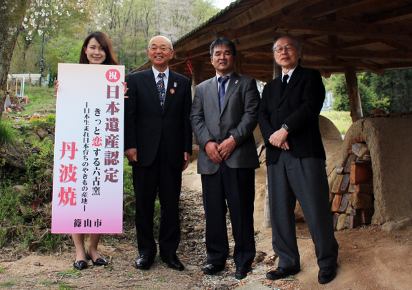 女性が日本遺産認定の看板を持ち、市長と兵庫県立陶芸美術館の三木館長、丹波焼陶磁器協同組合の市野 清治理事長と一緒に記念写真