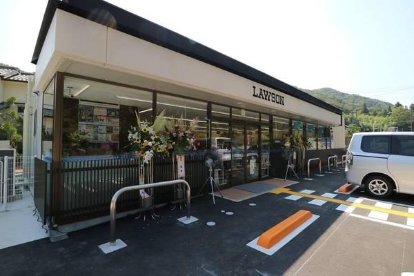 白と黒の外壁で新装開店のお花が店先に飾ってあるローソンの写真