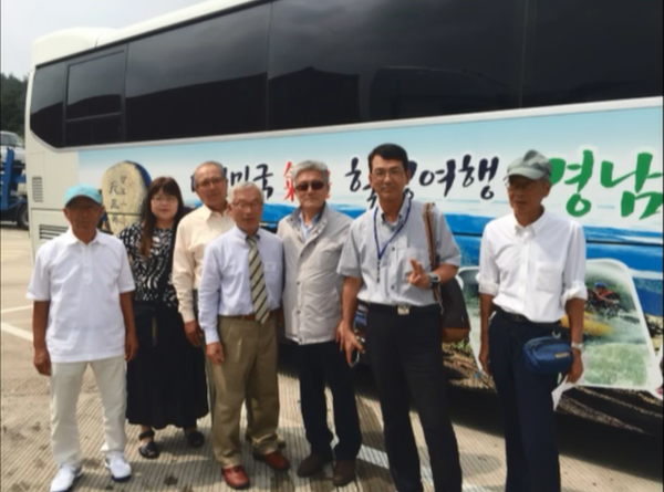 山清郡訪問団の7名がハングル文字の書かれたバスの前で記念撮影の写真