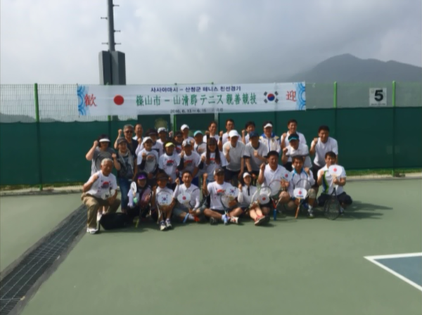 篠山市と山清郡とのテニス親善競技の参加者が集まってガッツポーズをして写っている集合写真