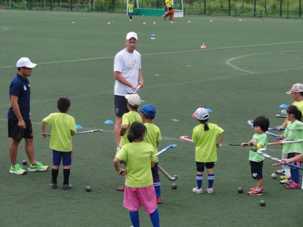 黄緑のティシャッを着た子供達が、先の曲がった棒を手に持ちルーク選手のお話を聞いている写真
