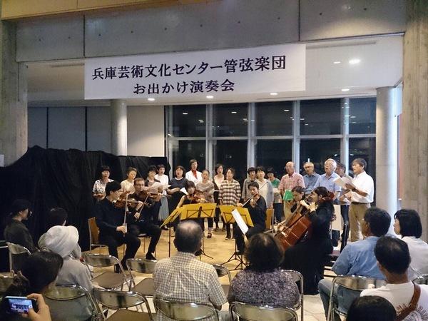 管弦楽団の演奏に合わせて合唱しているのを鑑賞している人々の写真