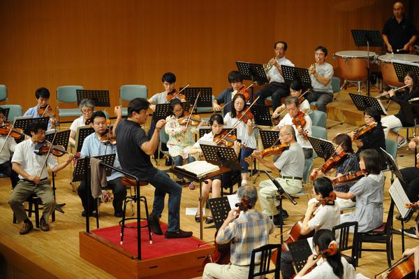 指揮者に合わせて管弦楽団が音合わせしている写真