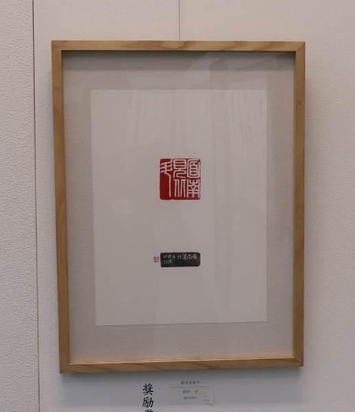 透明のガラスケースに入れられている、赤い朱肉で印が押されており、 篆書体(てんしょたい)で書かれた文字が写っている「面南見北斗」の作品の写真