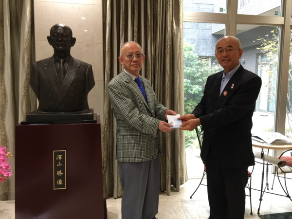 澤山 勝像の横で、市長が澤山 勝さんからふるさと納税を手渡しで頂いている様子の写真