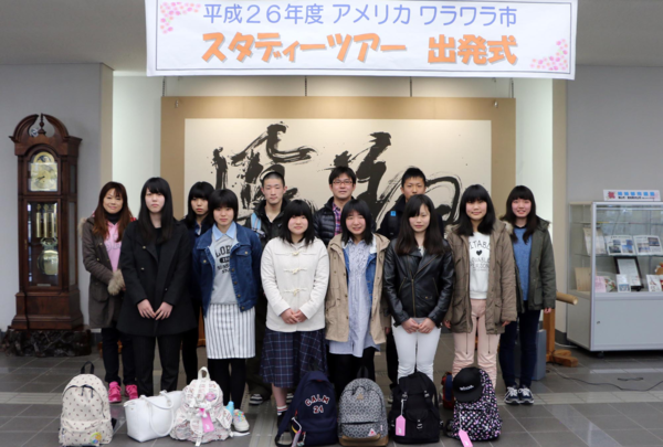 リュックを足元に置きみんなで集まって記念撮影をしている写真