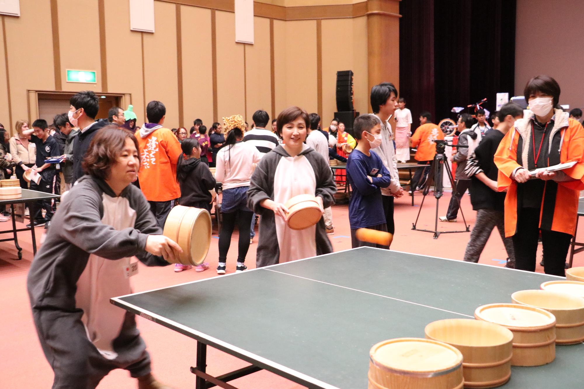 体の中心部が白で他がグレーの動物のような着ぐるみを着た2人が試合をしている写真