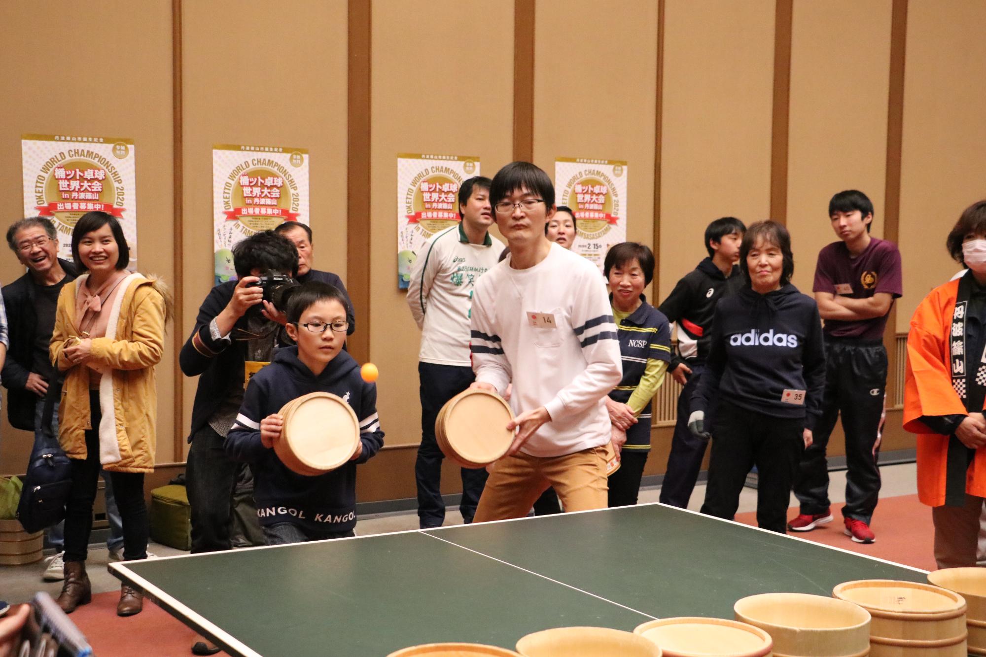 日本人チームの親子の息子さんがピンポン玉を打とうとしている写真