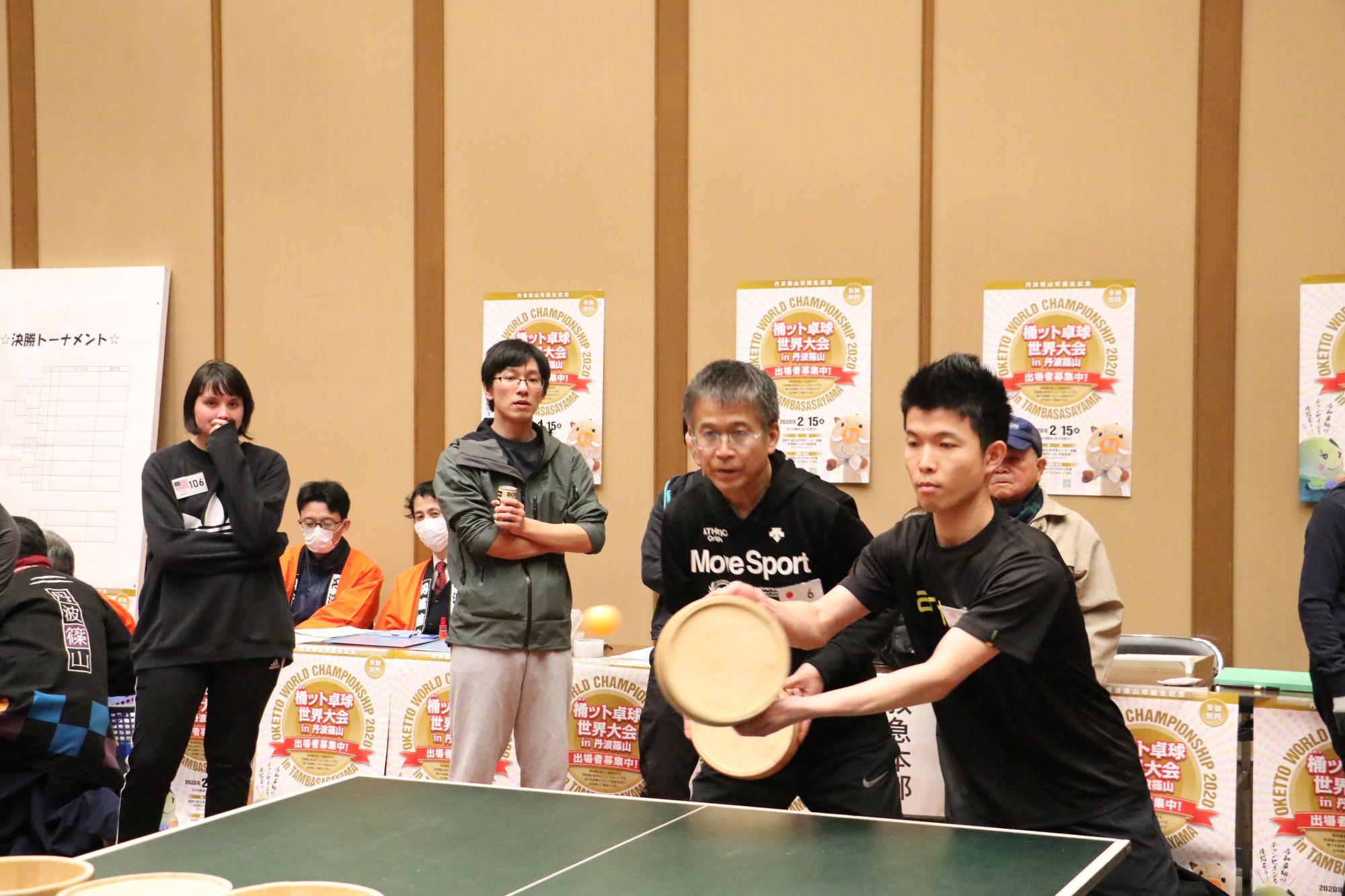 優勝した奥山チームの2人がコートで桶をもって試合をしている写真