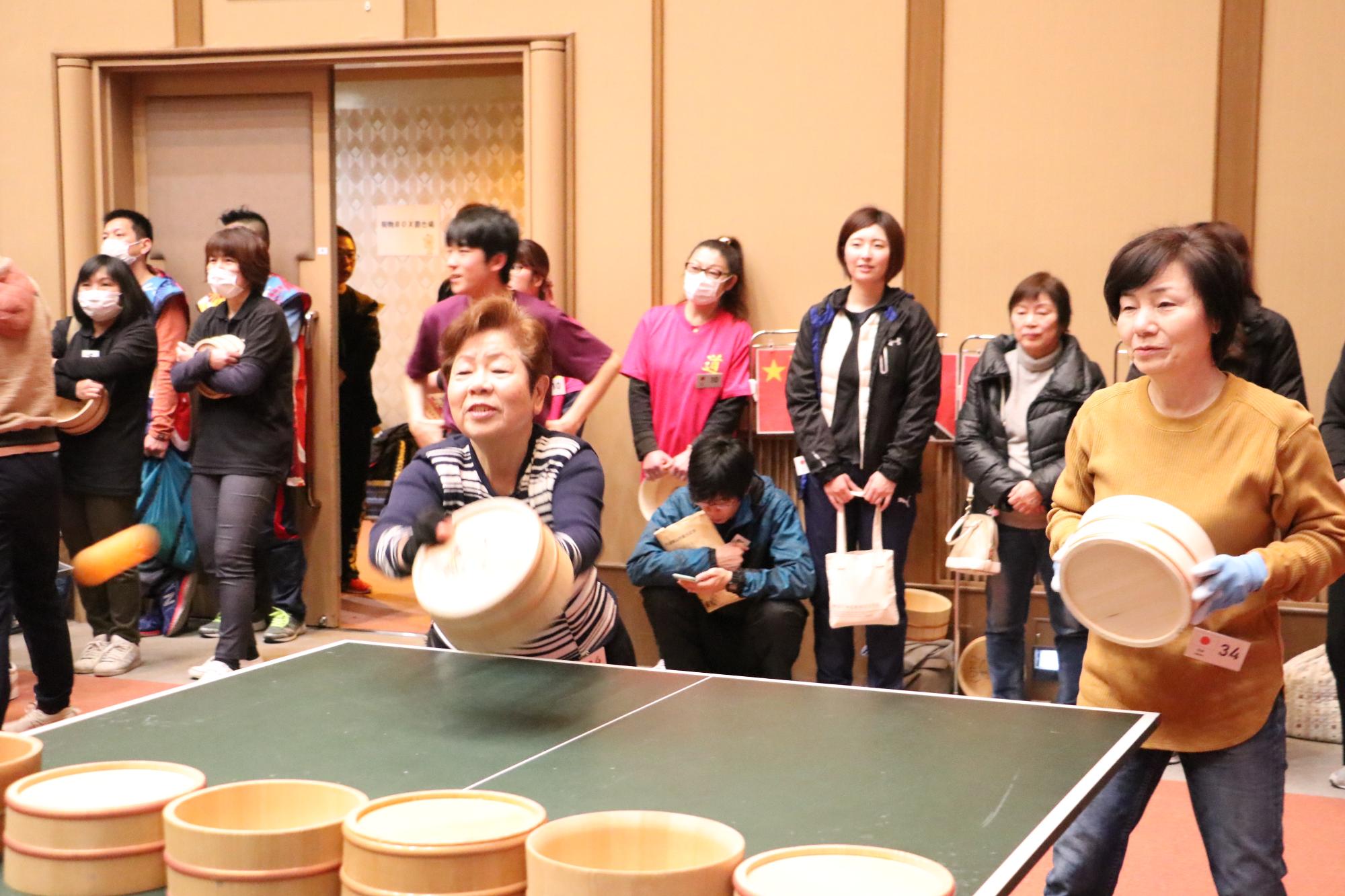 日本人チームの2人が桶をもって試合をしており、ピンポン玉をうった写真