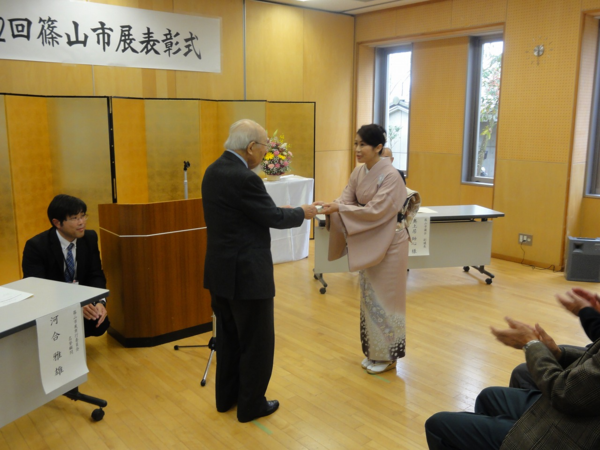 河合先生が着物姿の辻岡さんに記念品を渡している写真
