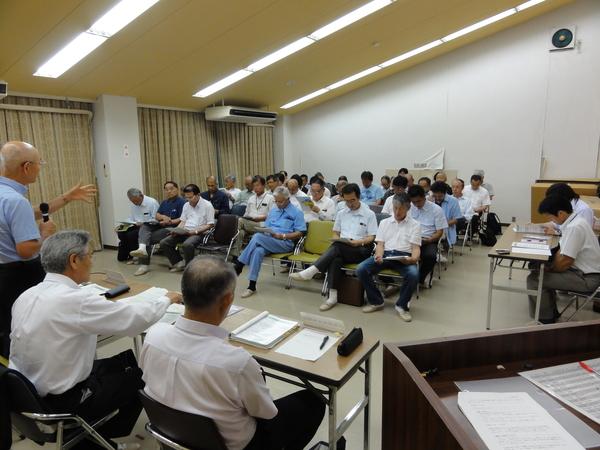 椅子に腰かけて資料を見ている参加者の方を向き、市長が話をしている写真