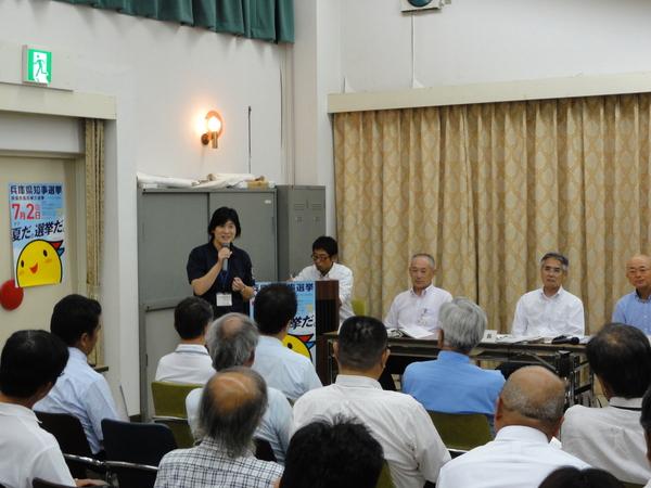 市長や関係者の方々が参加者と向かい合って座っており、左前方で押部校長先生がマイクを持ちお話をされている写真