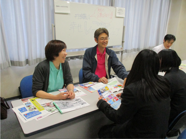 男女2人の企業の方がパンフレットで女子高生2人に笑顔で自分たちの会社の説明している写真