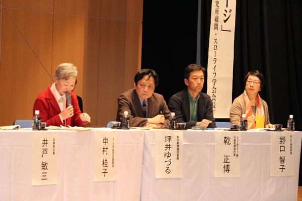 赤いジャケットを羽織った中村 桂子さんがマイクを持ってお話ししている写真