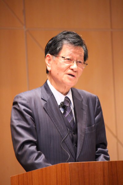 スーツを着た神野さんが舞台でお話ししているところをアップでうつした写真