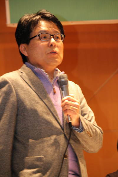 マイクを手に持ちスーツを着た増田さんがお話ししているところをアップでうつした写真