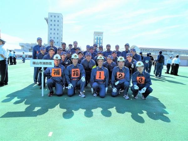 篠山市消防団のプラカードを持った、笑顔の団員たちの集合写真