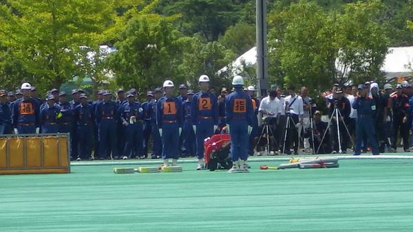 胸に番号のゼッケンをつけている団員2名と指のゼッケンをつけて団員が整列している写真