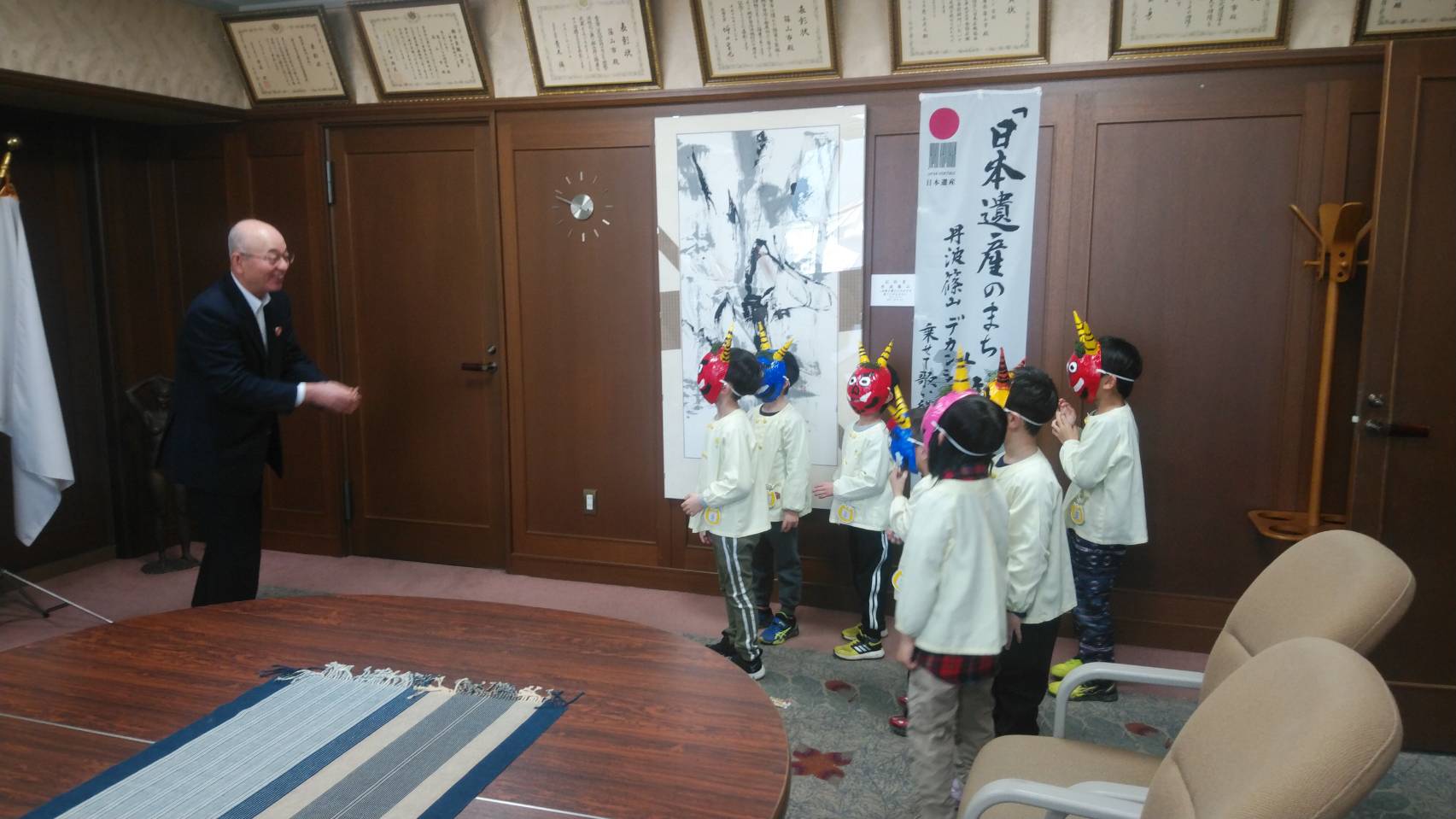 鬼のお面をかぶった子どもたちが、酒井市長にむけて豆を投げている写真