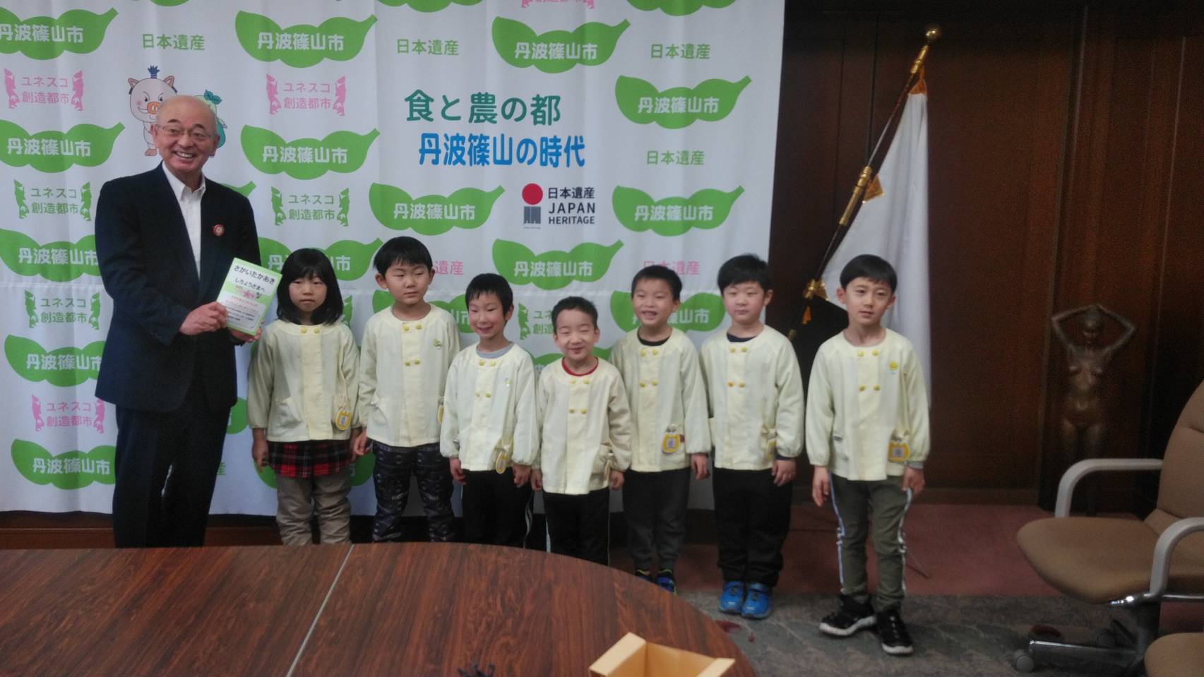 7人の園児のみなさんと、卒園式の案内をもらった酒井市長が一列に並んでいる写真