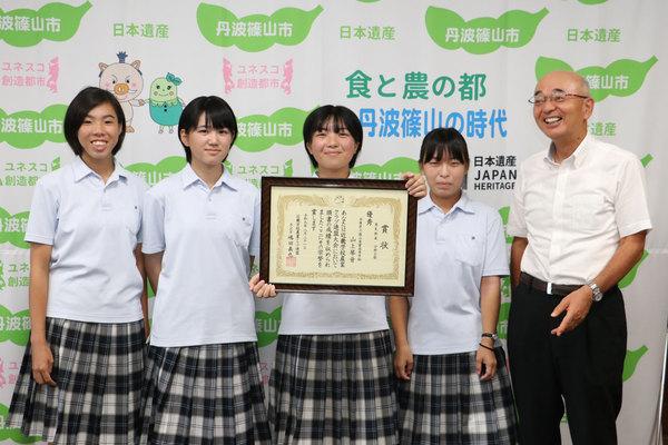 賞状を持つ山上さんを中心にした女生徒4人と市長が映っている写真