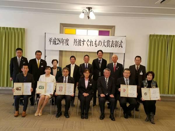 「丹波すぐれもの大賞の表彰式」にて受賞者が賞状の入った額を手に持ち市長らと一緒に記念撮影している写真