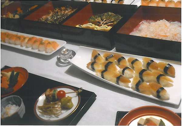 お盆に取り分けらけた料理があり、寿司、なますや玉子焼きの入ったお重の写真