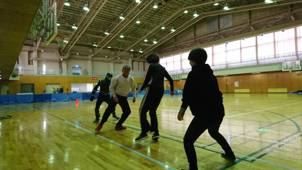 体育館にて、反復横跳びをしている市長とご当地ヒーローのササグロと男性2名の写真