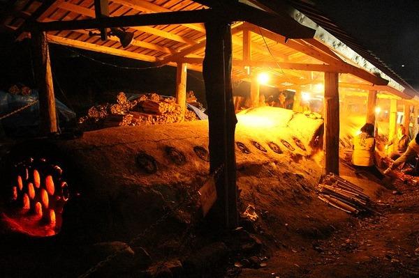 夜にライトが照らされ、手作りの窯から火がついている写真