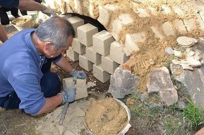 男性が石を削って、窯を作っている写真