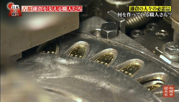 テレビ画面に映し出された機械の型にはめられた金の金具