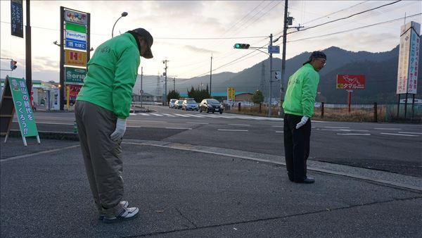 市長と男性が交差点で道路に向かいあいさつをしてお辞儀をしている写真