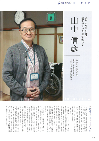 山中 信彦さんが両手を前で組んでグレーのカーディガンを着た上半身が写っている写真と山中さんが紹介されている雑誌の記事が載っていいる写真