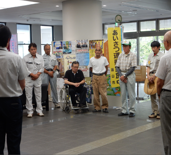 作業着を着た篠山市鉄工組合の方々が円になって話を聞いている様子の写真