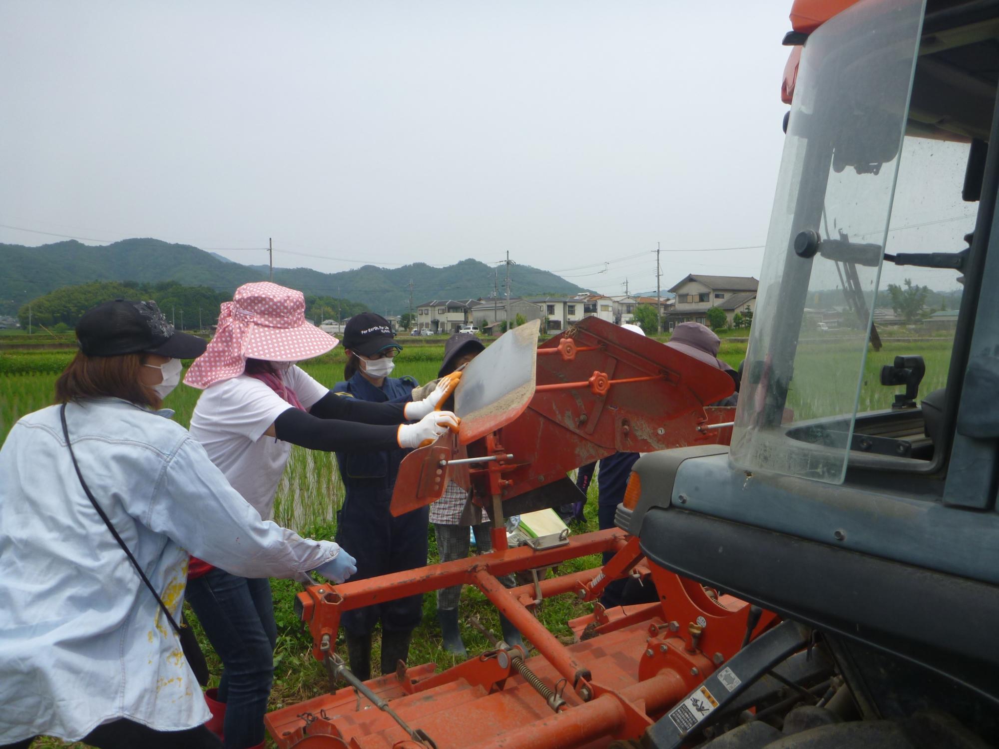 トラクターの調整の仕方を教えてもらうオペレーターたち